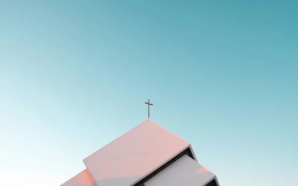 A church roof peak with a cross against a clear blue sky
